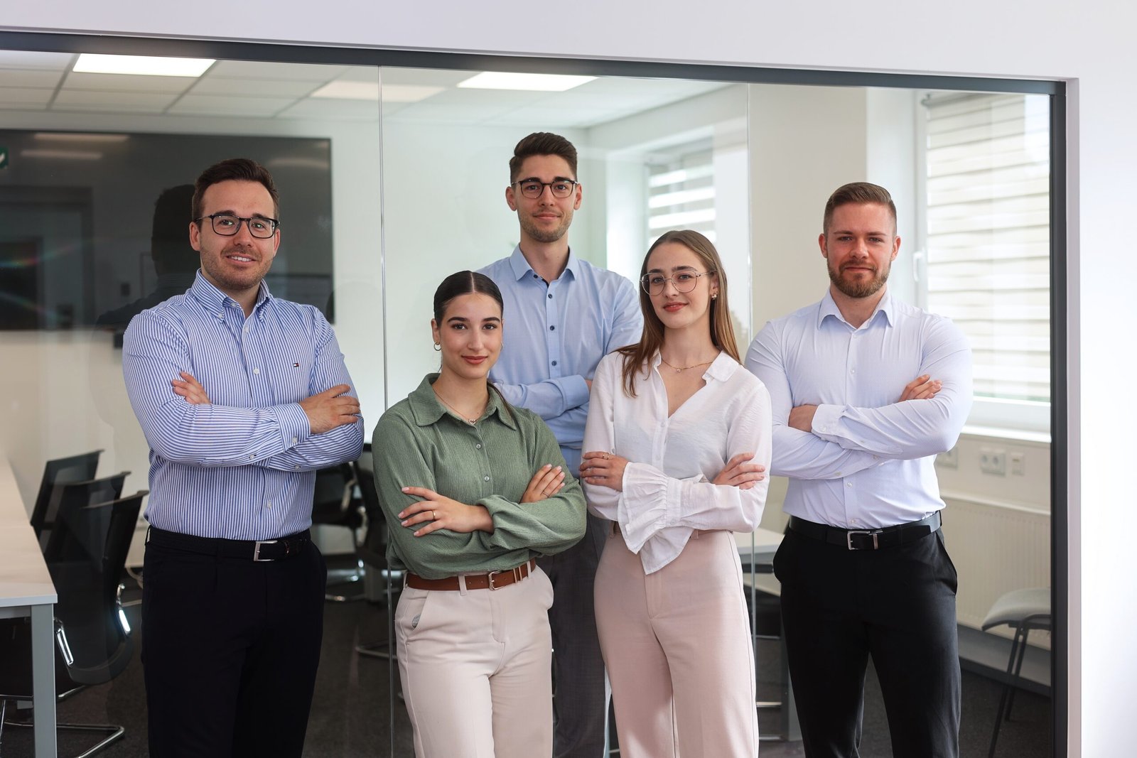 Teamfoto Norentec GmbH mit fünf Personen vor Glasscheibe im Büro